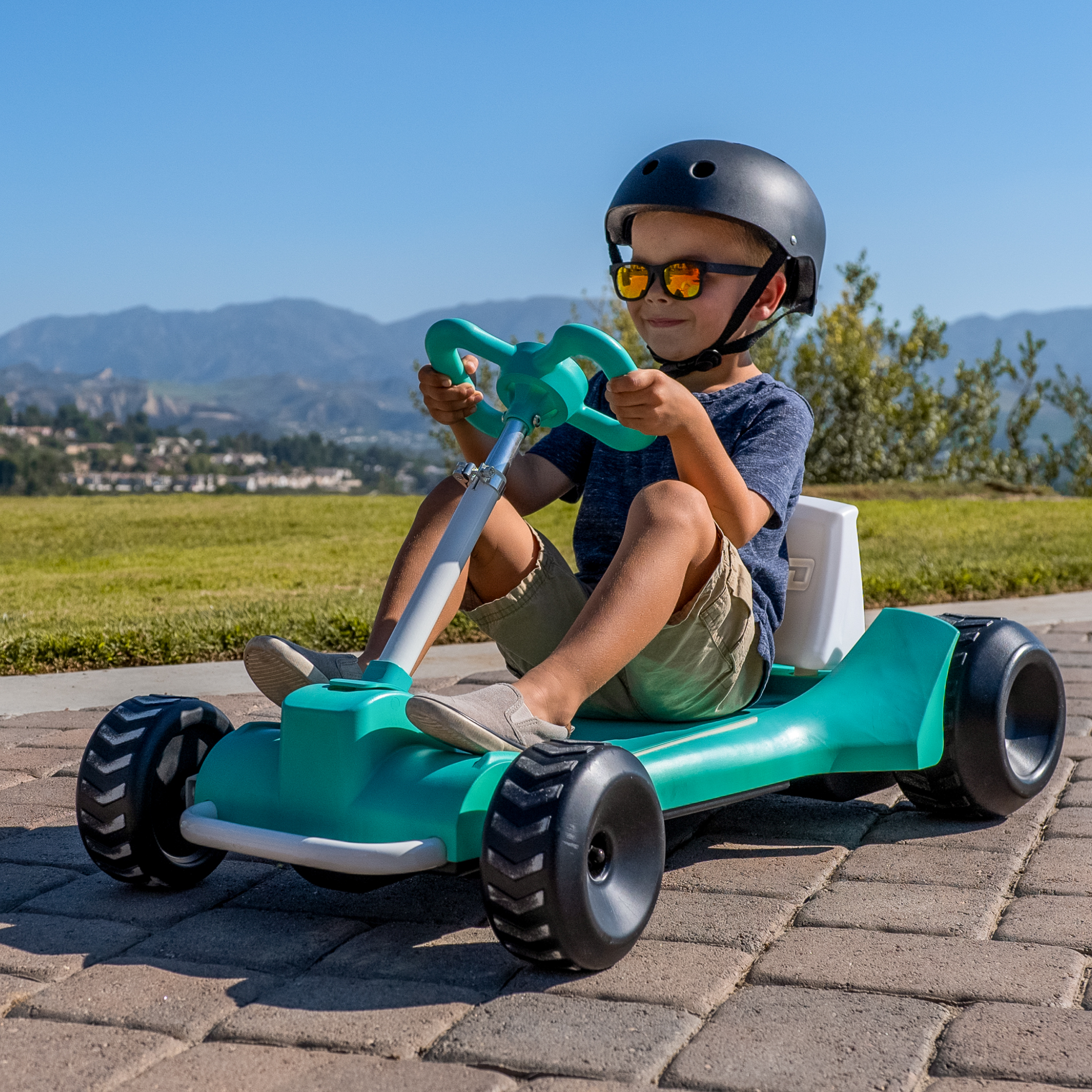 Boy in sunglasses riding in teal Zypster outside