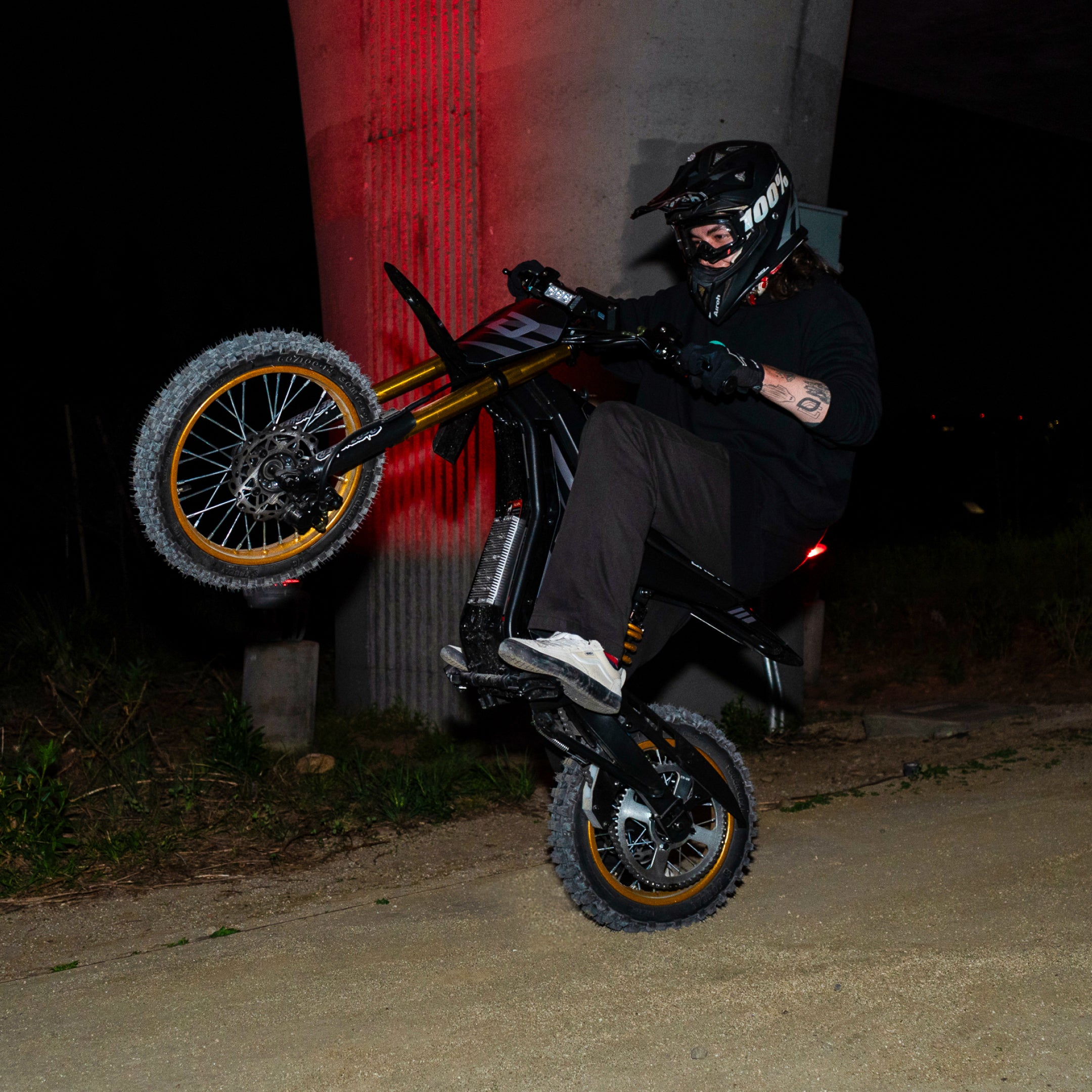 Person on a motorcycle performing a wheelie at night.