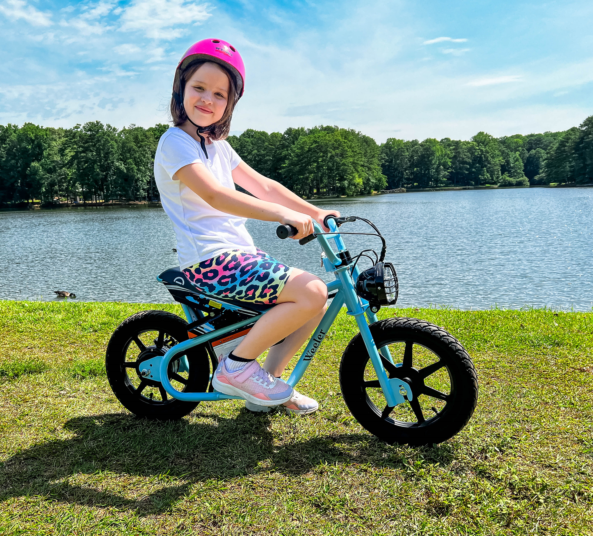 Young girl on Droyd electric Weeler bicycle in front of lake